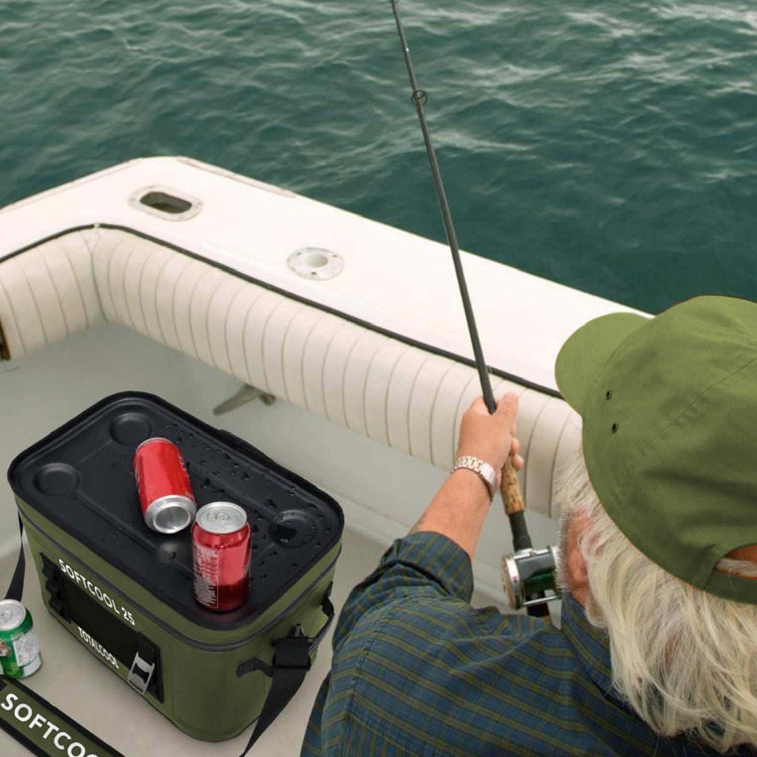 Image of an older man fishing on a boat with a softcool 25 to keep beverages / fish cool